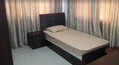 a small bed with a wooden headboard and a night stand at Shahed Apartment in Amman