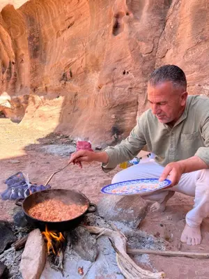 a man holding a plate of food over a fire at Quite bubble tent in Wadi Rum