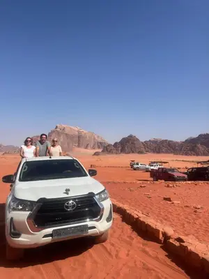three people sitting in the back of a white suv in the desert at Quite bubble tent in Wadi Rum