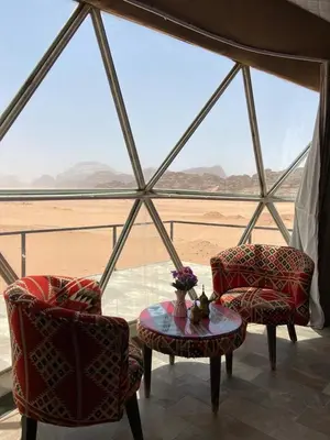 a room with two chairs and a table with a view of the desert at Wadi Rum Desert Tours and Glamping with Hussein in Wadi Rum