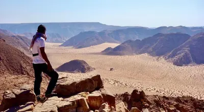 a woman standing on top of a mountain overlooking the desert at Wadi Rum Desert Tours and Glamping with Hussein in Wadi Rum