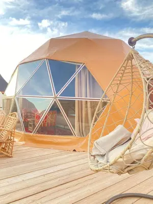 a dome tent on a deck with a chair at Wadi Rum Desert Tours and Glamping with Hussein in Wadi Rum