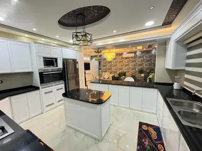 a kitchen with white cabinets and a black counter top at شقق فندقية فاخرة in Amman