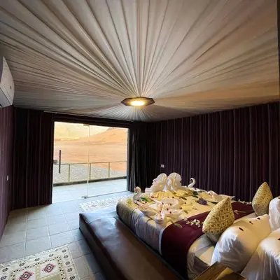 a bedroom with a large bed and a large window at Magical desert camp in Disah