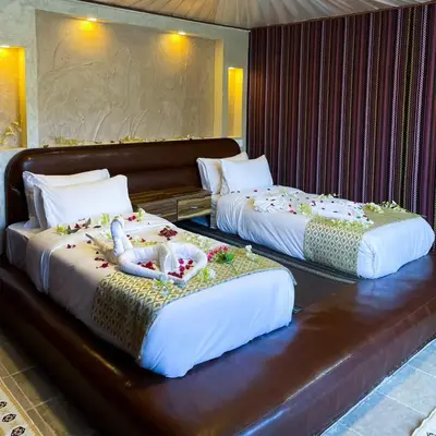 two beds in a hotel room with flowers on them at Magical desert camp in Disah