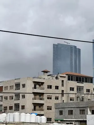 a building with a tall skyscraper in the background at Gentle Breeze Studio 3 in Amman