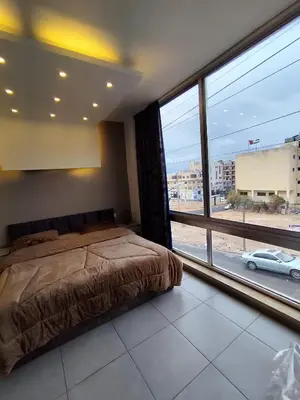 a bedroom with a bed and a large window at Gentle Breeze Studio 3 in Amman
