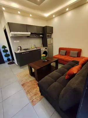 a living room with a couch and a kitchen at Gentle Breeze Studio 3 in Amman