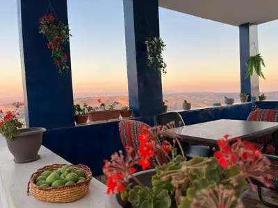a table with a basket of fruit and flowers on a balcony at Al-Bustan House& Umm Qais in Um Qeis