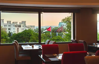 a restaurant with tables and chairs and a large window at Oryx Hotel Aqaba in Aqaba