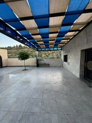 a large building with a blue roof with a tree in the middle at البيت الريفي in Jerash