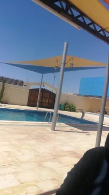 a view of a swimming pool with a blue canopy at Al-Karak Countryside and hotel in Ad Dimnah