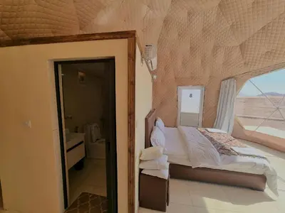 a bedroom with a bed in a room with a window at Glow of Wadi Rum Camp in Wadi Rum
