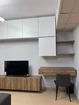a living room with a tv and white cabinets at new furnished studio gardens st 329 in Amman