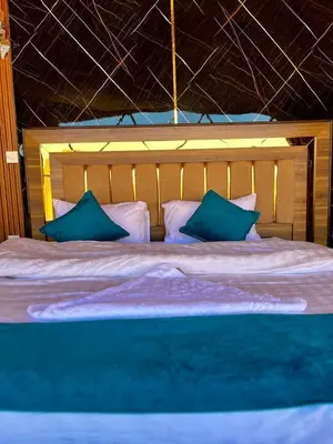 a bedroom with a large bed with blue pillows at Desert Boulevard Camp in Wadi Rum