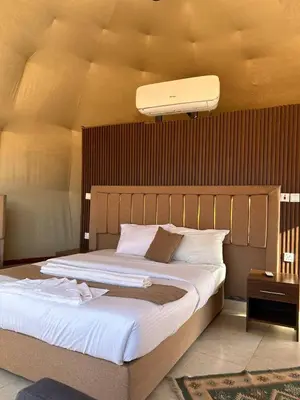 a bedroom with a large bed with a light above it at Desert Boulevard Camp in Wadi Rum