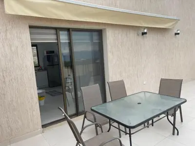 a glass table and chairs in front of a building at Deadsea Elite second floor shared swimming pool in Sowayma
