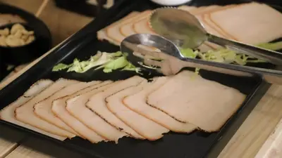 a tray of food with meat and salad with a serving spoon at Sandy palace Hotel in Amman