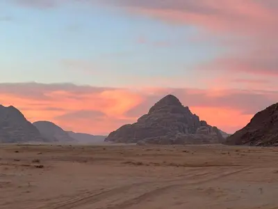 a sunset over the desert with mountains in the background at Wadi Rum Magic Stars in Wadi Rum