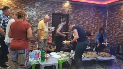a group of people standing around a table with food at Margaret from Petra cave house in Wadi Musa