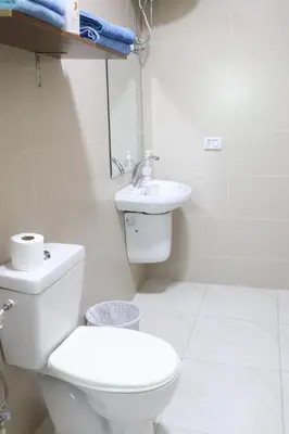 a white bathroom with a toilet and a sink at Salvador Dali Apartments in Amman