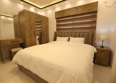 a bedroom with a large white bed with a wooden headboard at Third circle Luxury Hotel apartment in Amman