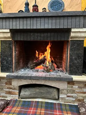 a brick fireplace with a fire in it at Bedouin family home in Wadi Musa