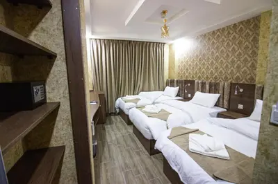 a hotel room with three beds and a television at Beirut Hotel 2 in Amman
