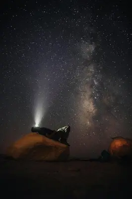 a person sitting on a rock under a starry sky at Wadi Rum Backpacker Camp in Wadi Rum