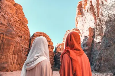 two women walking through the desert near rocks at Wadi Rum Backpacker Camp in Wadi Rum