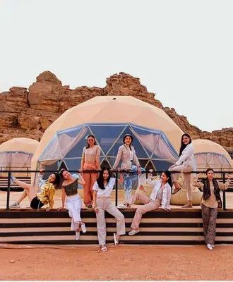 a group of people sitting on steps in front of a tent at Enjoy Camp Bubble Luxury with Jeep Tour in Wadi Rum