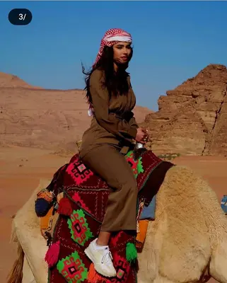 a woman riding on the back of a camel in the desert at Enjoy Camp Bubble Luxury with Jeep Tour in Wadi Rum