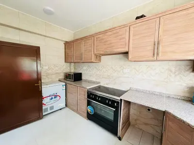 a kitchen with wooden cabinets and a black dishwasher at marram apartment in Aqaba