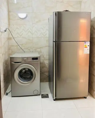 a stainless steel refrigerator next to a washing machine at marram apartment in Aqaba