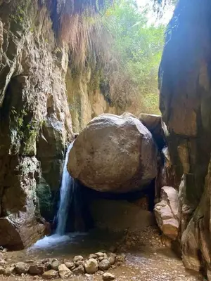 a waterfall in a cave with a large rock at Dana star in Dana