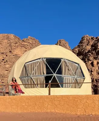 a woman standing in front of a dome tent at Nada luxury camp in Wadi Rum
