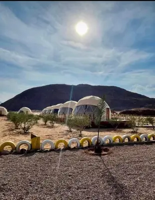 a group of domes in a field with a mountain at Khaled Rum Camp in Disah