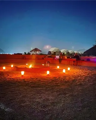 a fire pit with candles in a field at night at Khaled Rum Camp in Disah
