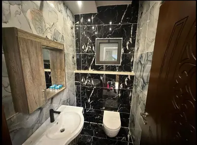 a black tiled bathroom with a sink and a toilet at شقق فندقية فاخرة in Amman