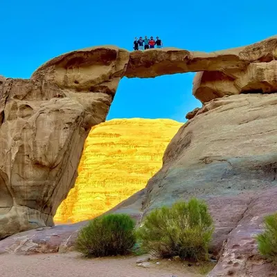 three people standing on top of a rock bridge at Moon City Luxury Tent in Wadi Rum