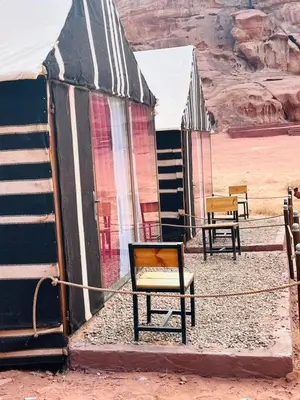 a group of chairs sitting next to a building in the desert at Moon City Luxury Tent in Wadi Rum