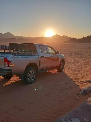 a truck parked in the desert at sunset at Faiesal Luxury camp & Tour in Wadi Rum