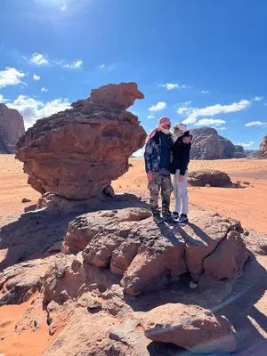 two people standing on a rock in the desert at Faiesal Luxury camp & Tour in Wadi Rum