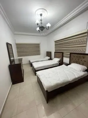 a bedroom with three beds and a chandelier at شقة مفروشة in Rujm Maghghijhah