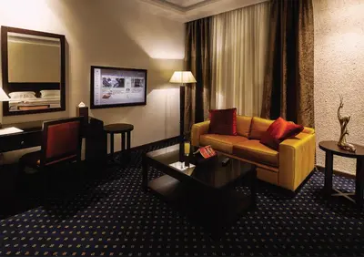 a living room with a couch and a desk in a hotel room at فندق سفن روزز in Amman