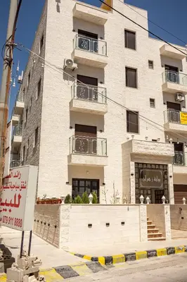 a tall white building with balconies on a street at Prestige hotel apartment in Amman