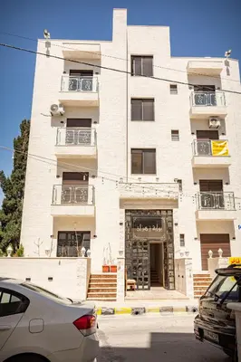 a tall white building with cars parked in front of it at Prestige hotel apartment in Amman