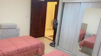 a bedroom with two beds and a mirror and a dresser at G Guest House in Amman