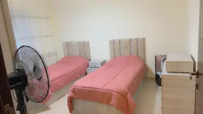 two beds with pink covers in a room at G Guest House in Amman