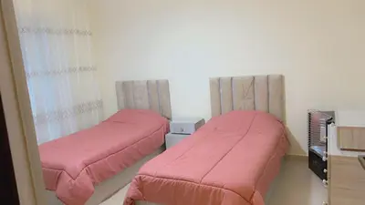 two beds with pink covers in a room at G Guest House in Amman